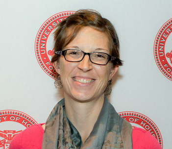 Dr. Kleinheider in front of UH Seal pasted on a white wall