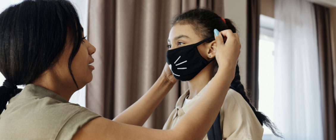 A mother helping her child with a face mask