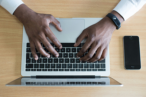 Black male typing on a laptop