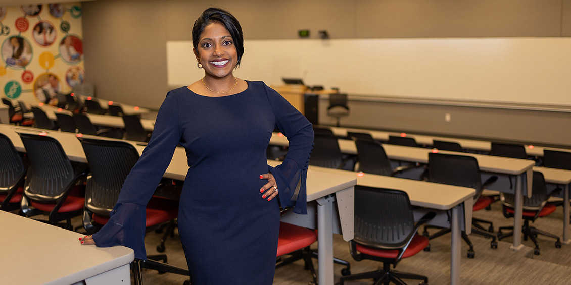 Varkey standing in a classroom and smiling into the camera 