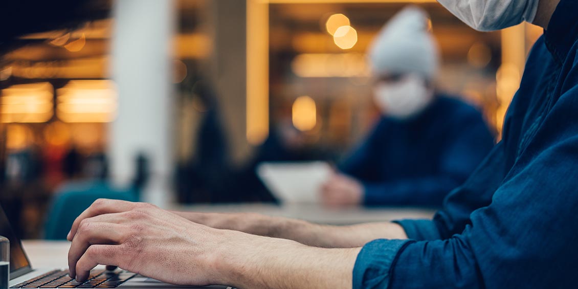 photo of masked person using laptop