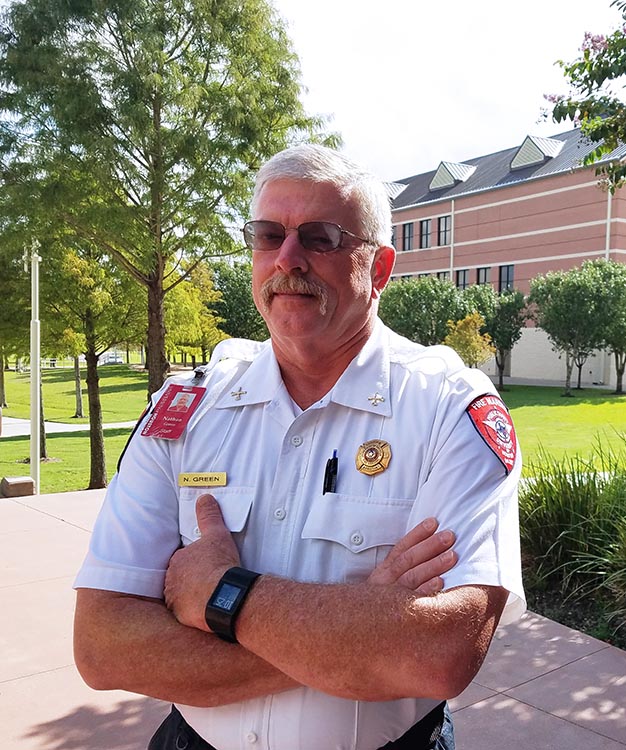 UH Assistant Fire Marshal standing in front of building with trees