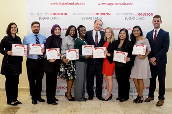 Group of people holding certificates standing together in front of a back drop