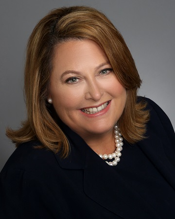 Portrait of a woman smiling in a black outfit with a pearl necklace