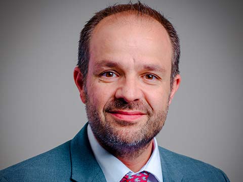 Portrait of a Hispanic man with a short faded beard in a blue business suit