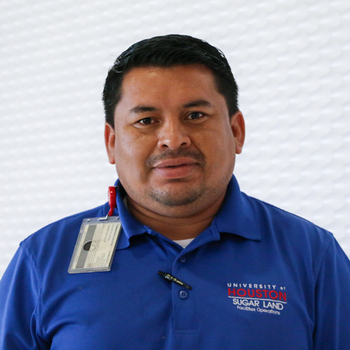 Portrait of a Hispanic man smiling wearing a blue polo shirt