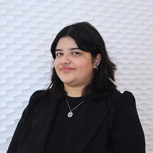 Portrait of a Hispanic woman smiling with dark shoulder length hair wearing a black business jacket