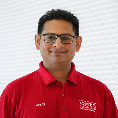 Portrait of an South Asian man smiling with glasses wearing a red polo shirt