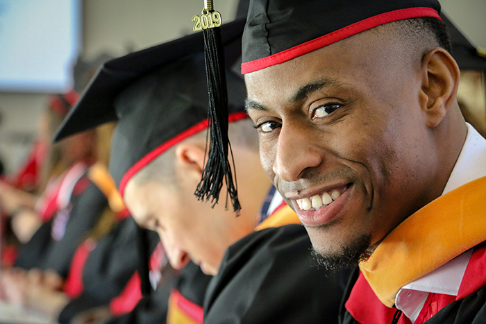 Close up a student wearing a graduation cap and gown looking at the camera