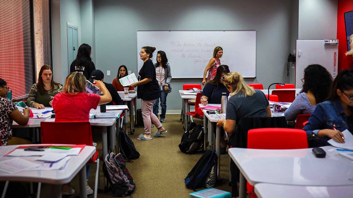 Students sitting at groups of tables and walking between stations.